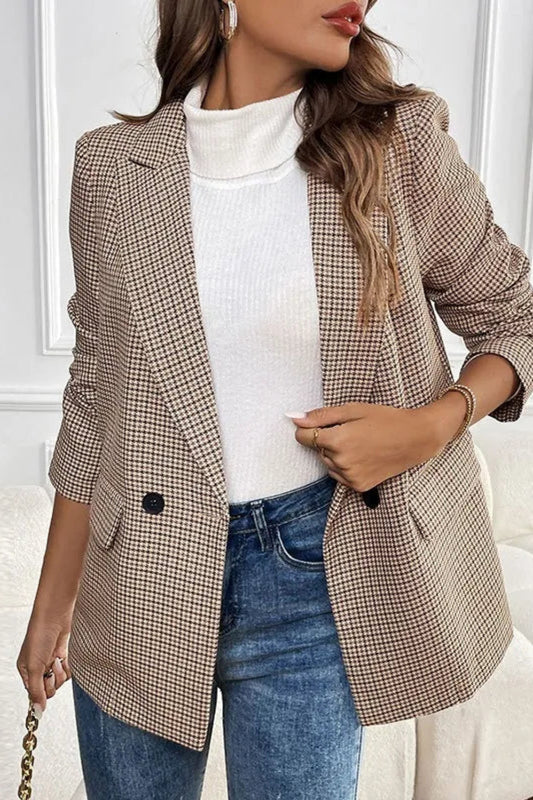 Woman wearing a plaid blazer over a white top and blue jeans in an indoor setting.