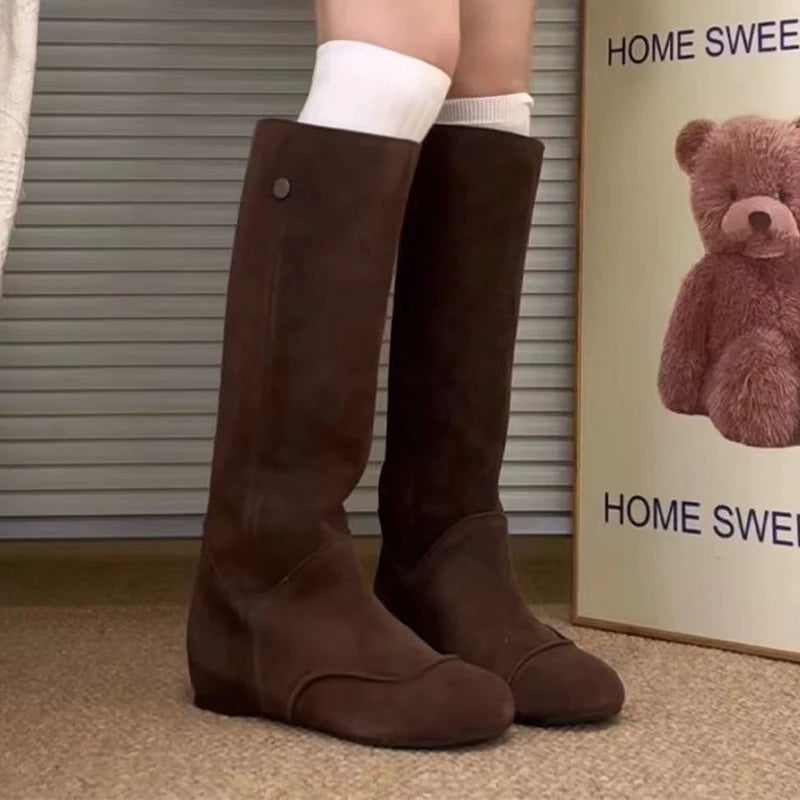 Brown knee-high boots worn with white socks, against a neutral background.