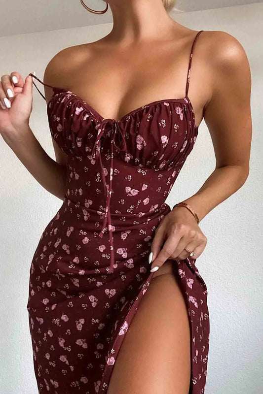 A woman wearing a red spaghetti strap floral midi dress with an O-neckline and side pockets.