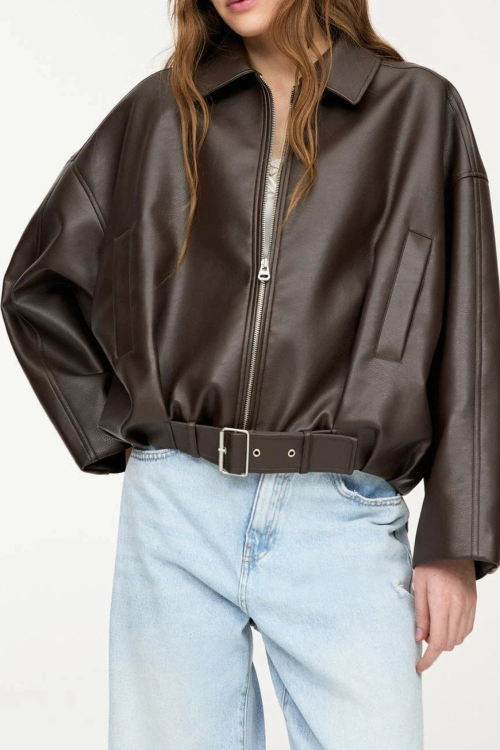 Person wearing a brown leather jacket and light blue jeans on a white background