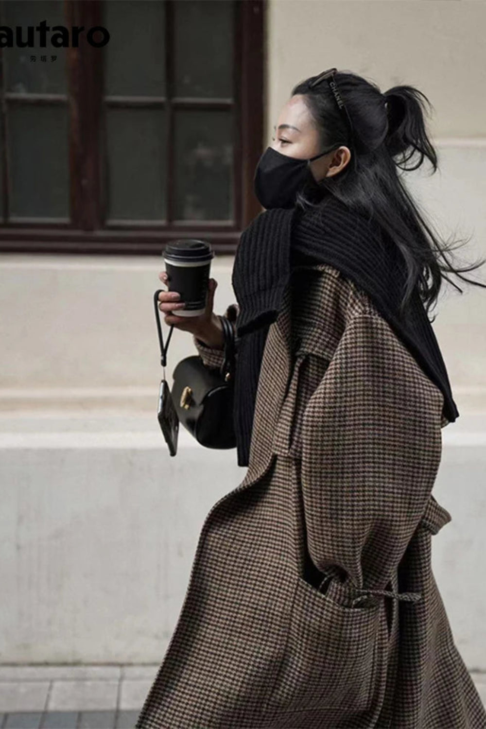 Person wearing a long coat and holding a coffee cup, with 'Lautaro' brand visible.