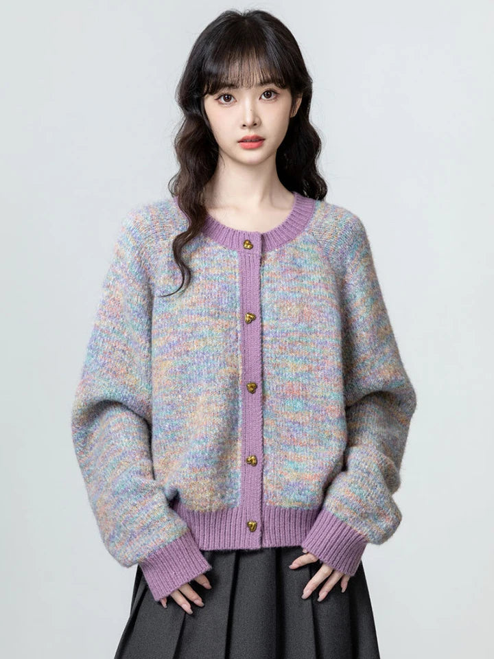 Woman wearing a colorful cardigan with a purple trim on a plain background