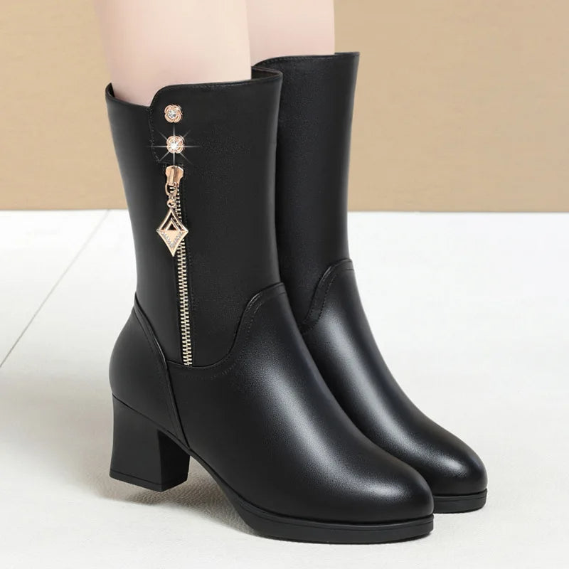 Black knee-high boots with decorative zipper on a light background