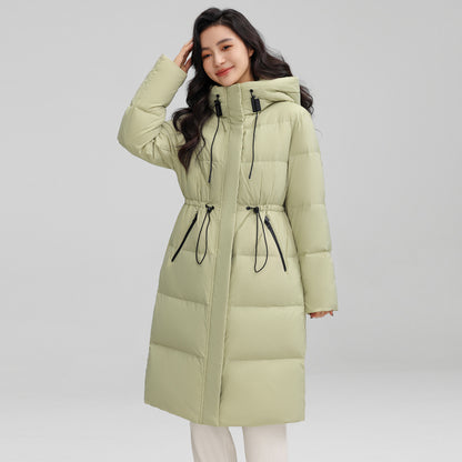 Woman wearing a light green puffer coat on a gray background