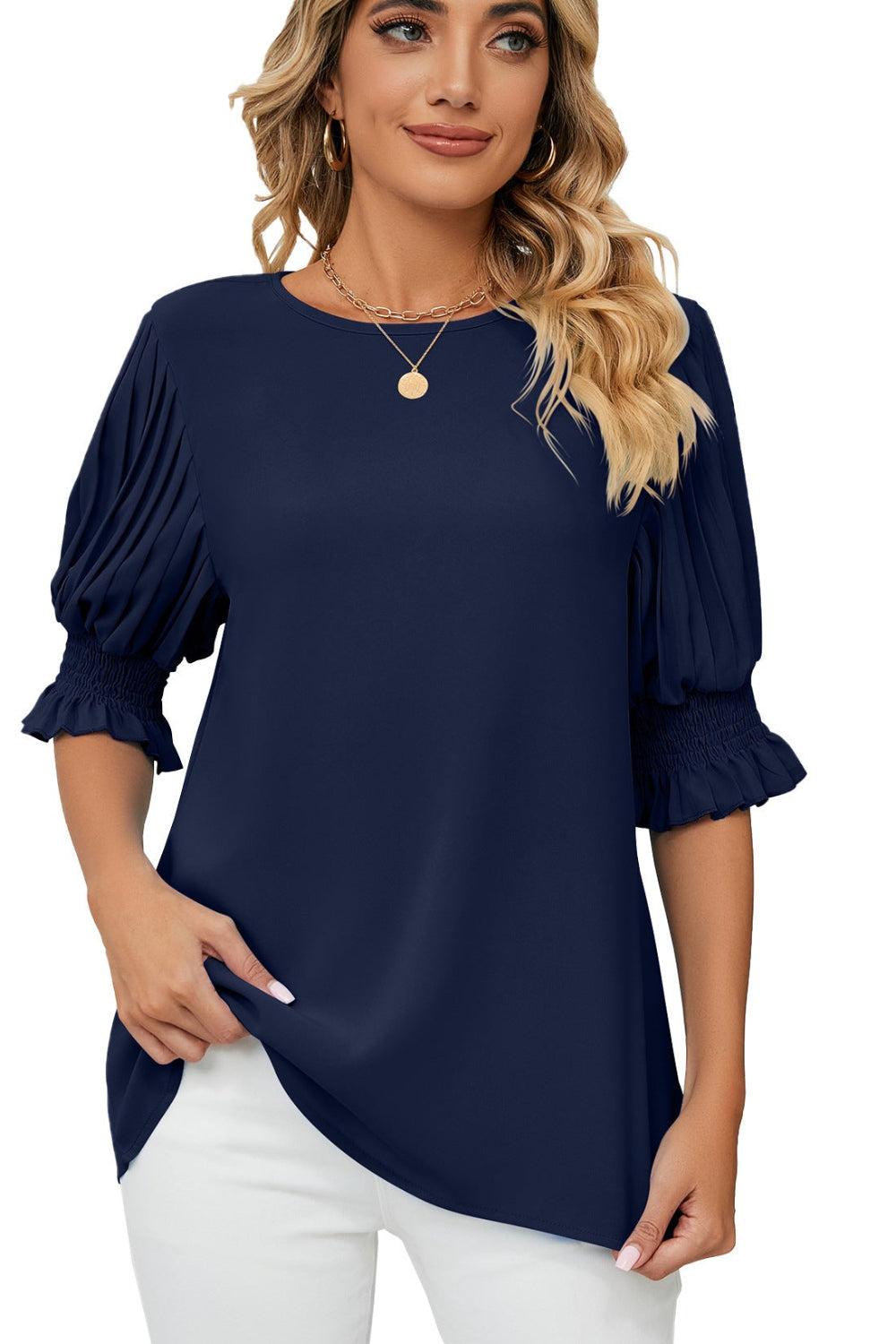 Woman wearing a navy blue blouse with white pants on a white background