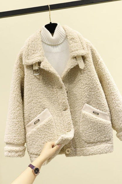 Beige sherpa jacket on a hanger against a beige wall