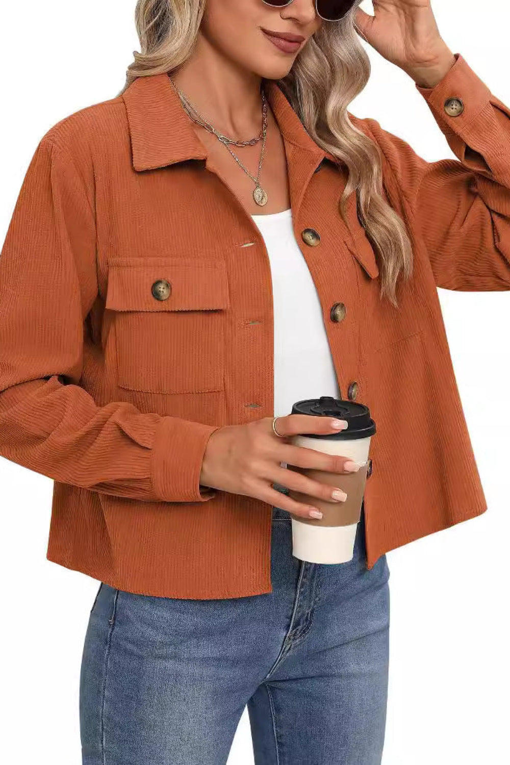 Woman wearing a brown corduroy jacket holding a coffee cup on a white background