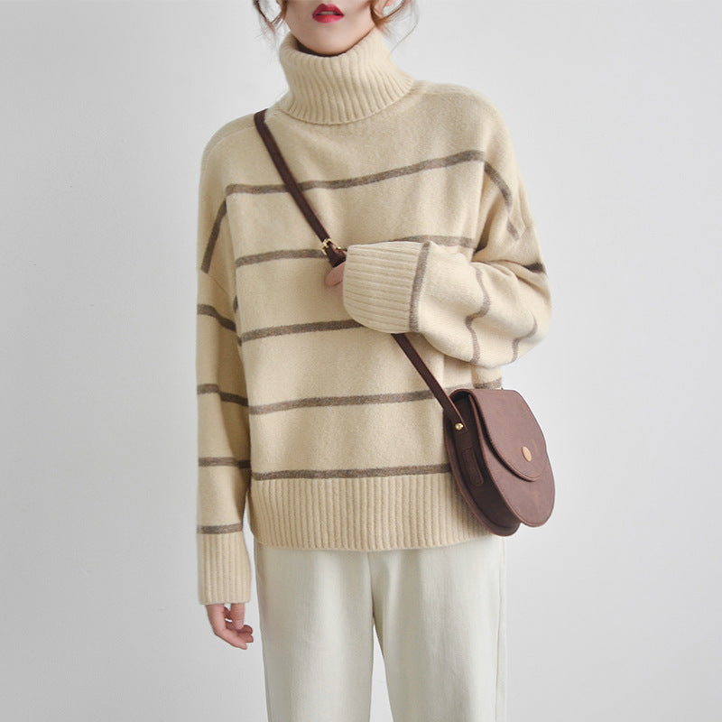 Person wearing a beige and brown striped sweater with a brown handbag on a light gray background