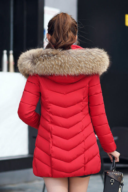 Person wearing a red puffer jacket with a fur-lined hood in an urban setting.