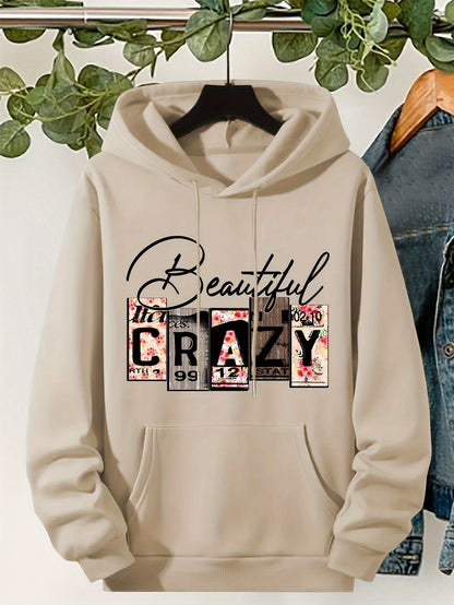Beige hoodie with 'Beautifully Crazy' design on a hanger with greenery in the background