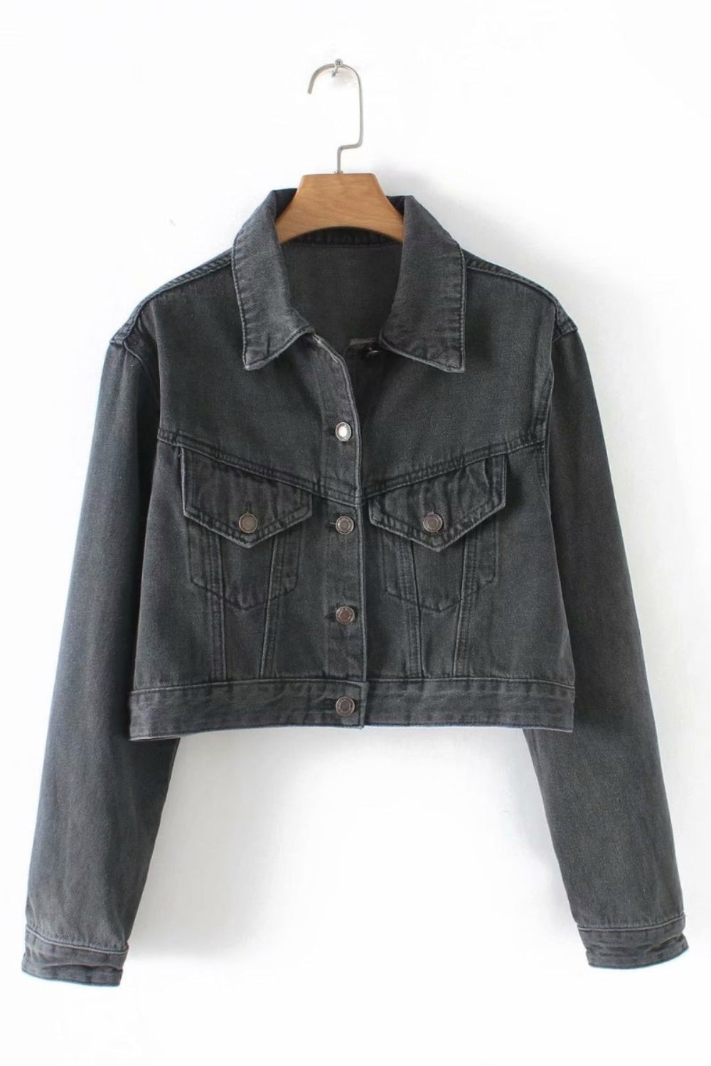 Black denim jacket on a hanger against a white background