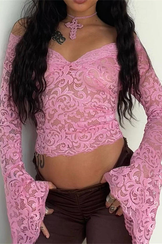 Person wearing a pink lace top with long sleeves against a plain background