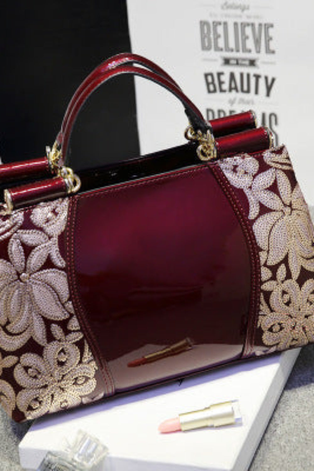 Designer handbag with floral lace detailing on a gray surface