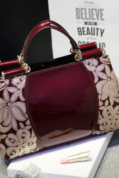 Designer handbag with floral lace detailing on a gray surface