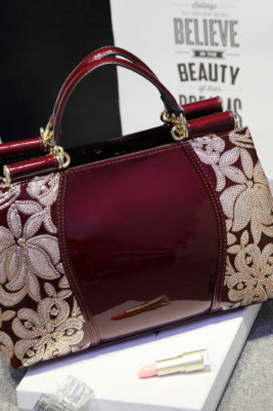 Designer handbag with floral lace detailing on a gray surface