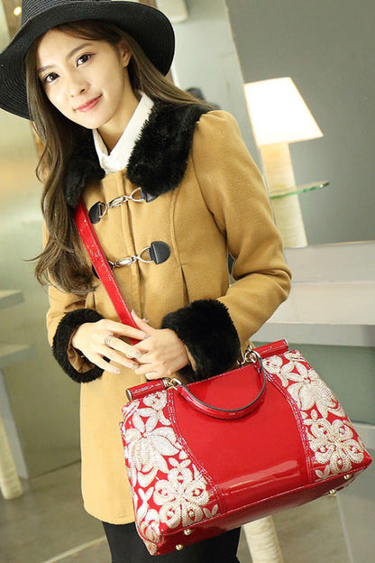 Woman holding a red handbag with white floral patterns in an indoor setting