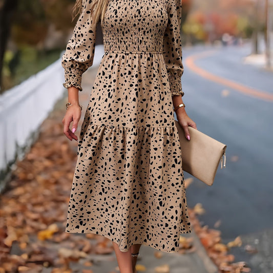 Woman wearing a beige dress with black polka dots holding a beige clutch on a street.