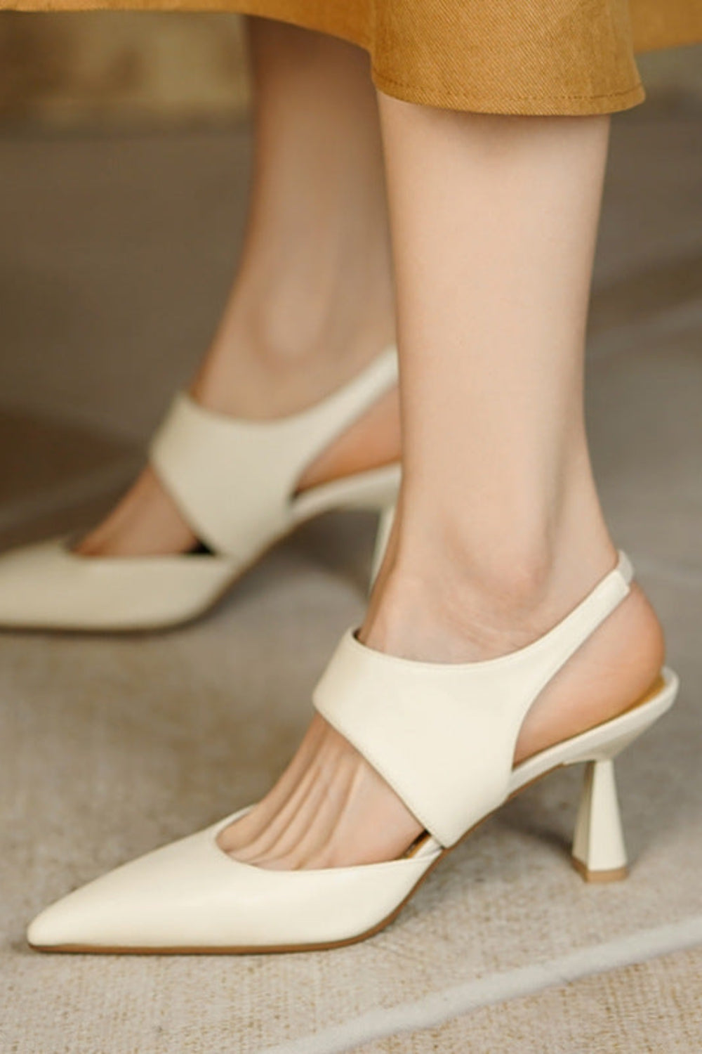 Beige high-heeled shoes worn by a person on a neutral background