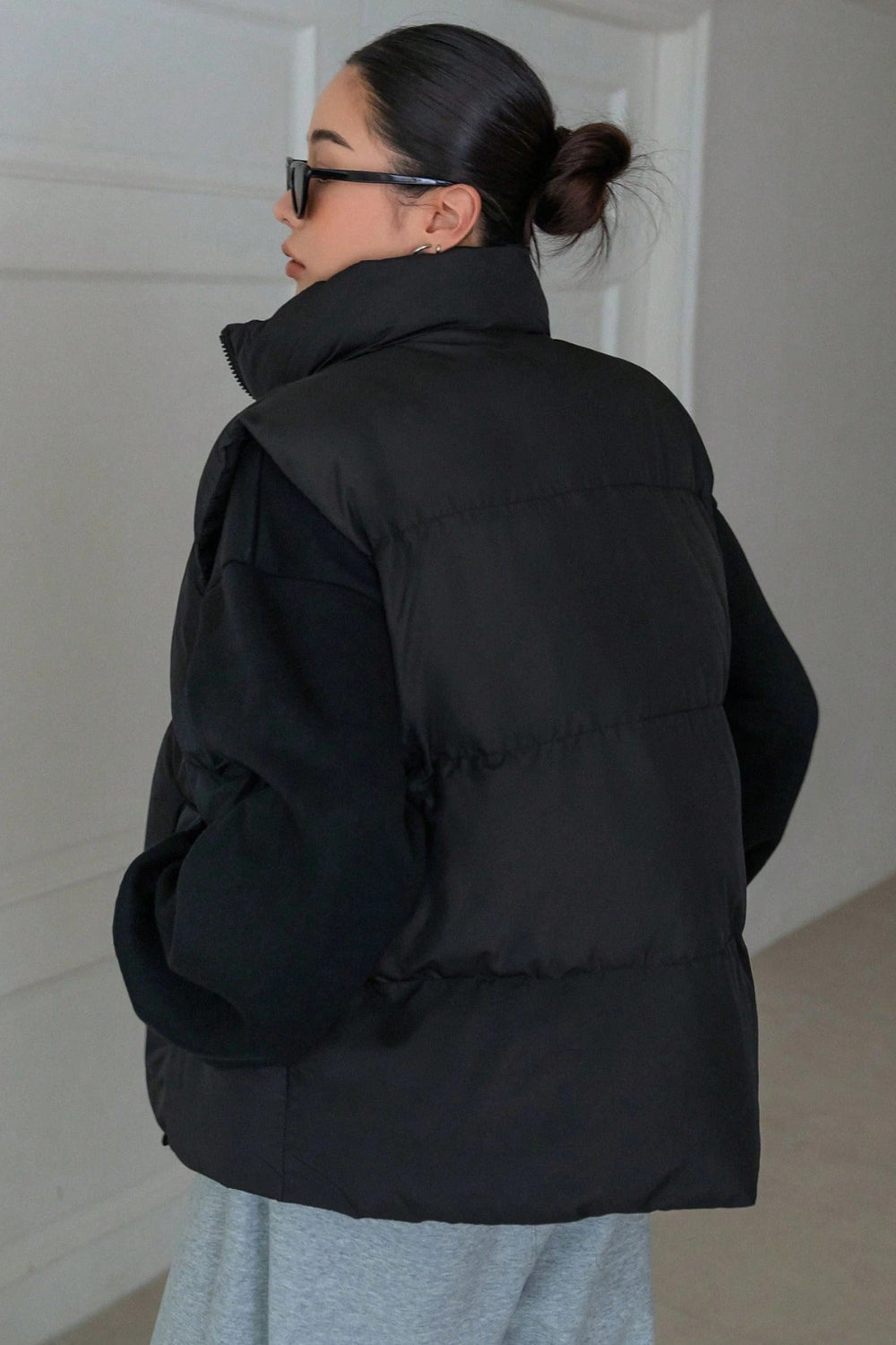 Person wearing a black puffer jacket in an indoor setting