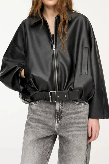 Person wearing a black leather jacket and gray jeans on a white background