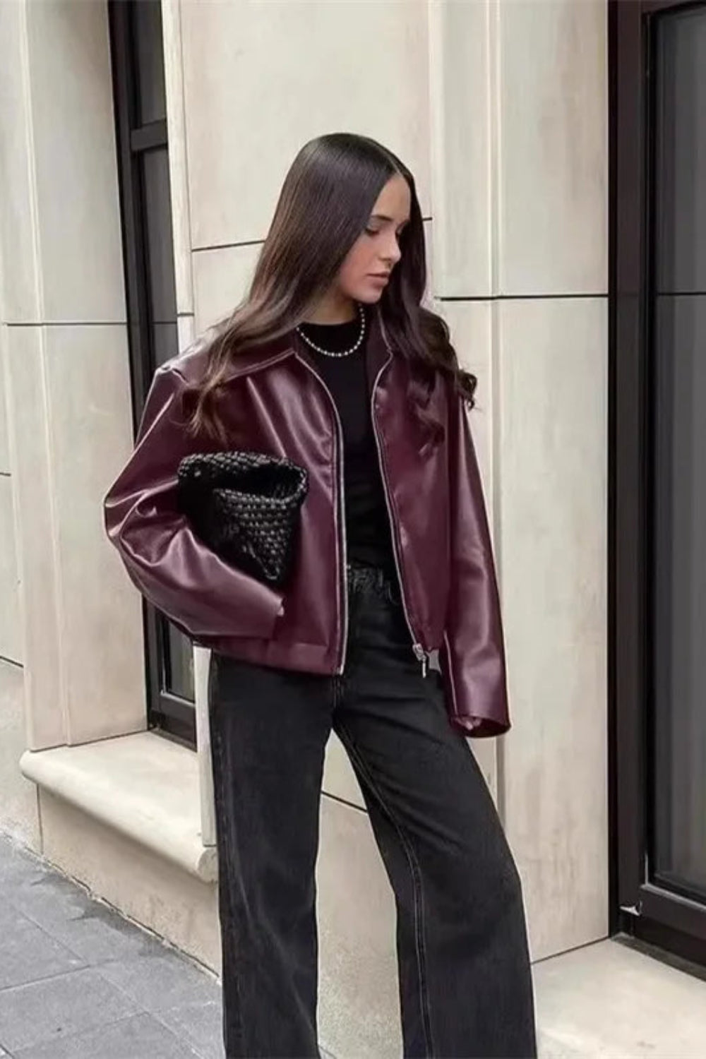 Woman wearing a purple jacket with a textured pocket design, standing on a city street.