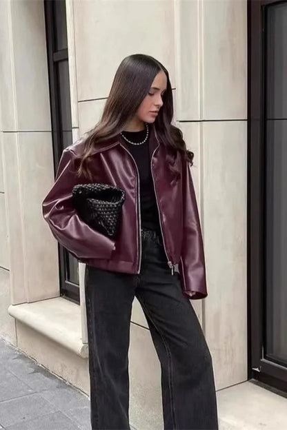Woman wearing a purple jacket with a textured pocket design, standing on a city street.
