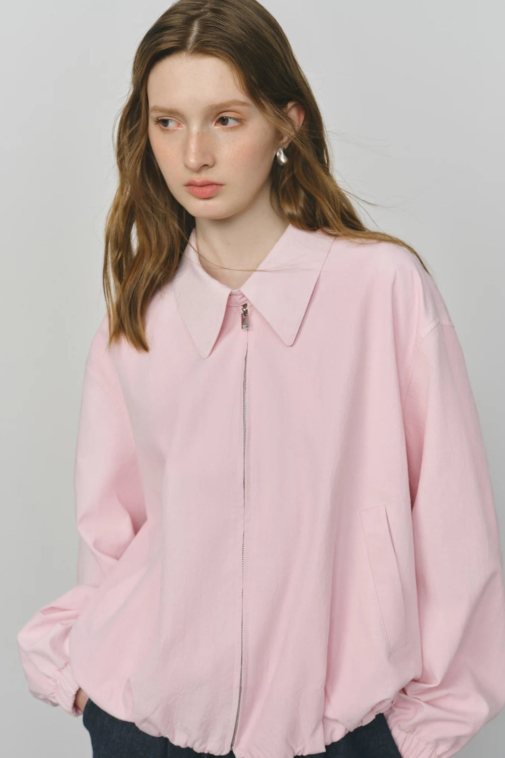 Woman wearing a light pink blouse against a plain background