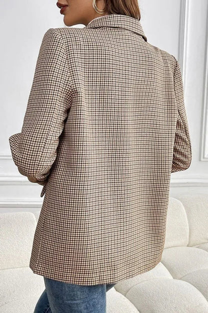 Person wearing a plaid blazer in a minimalistic room with white walls and furniture.