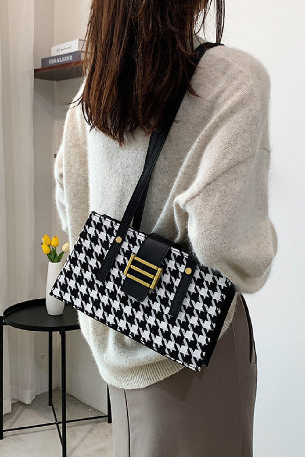 Person holding a black and white patterned handbag in an indoor setting