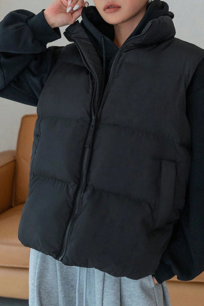 Person wearing a black puffer jacket with a neutral background