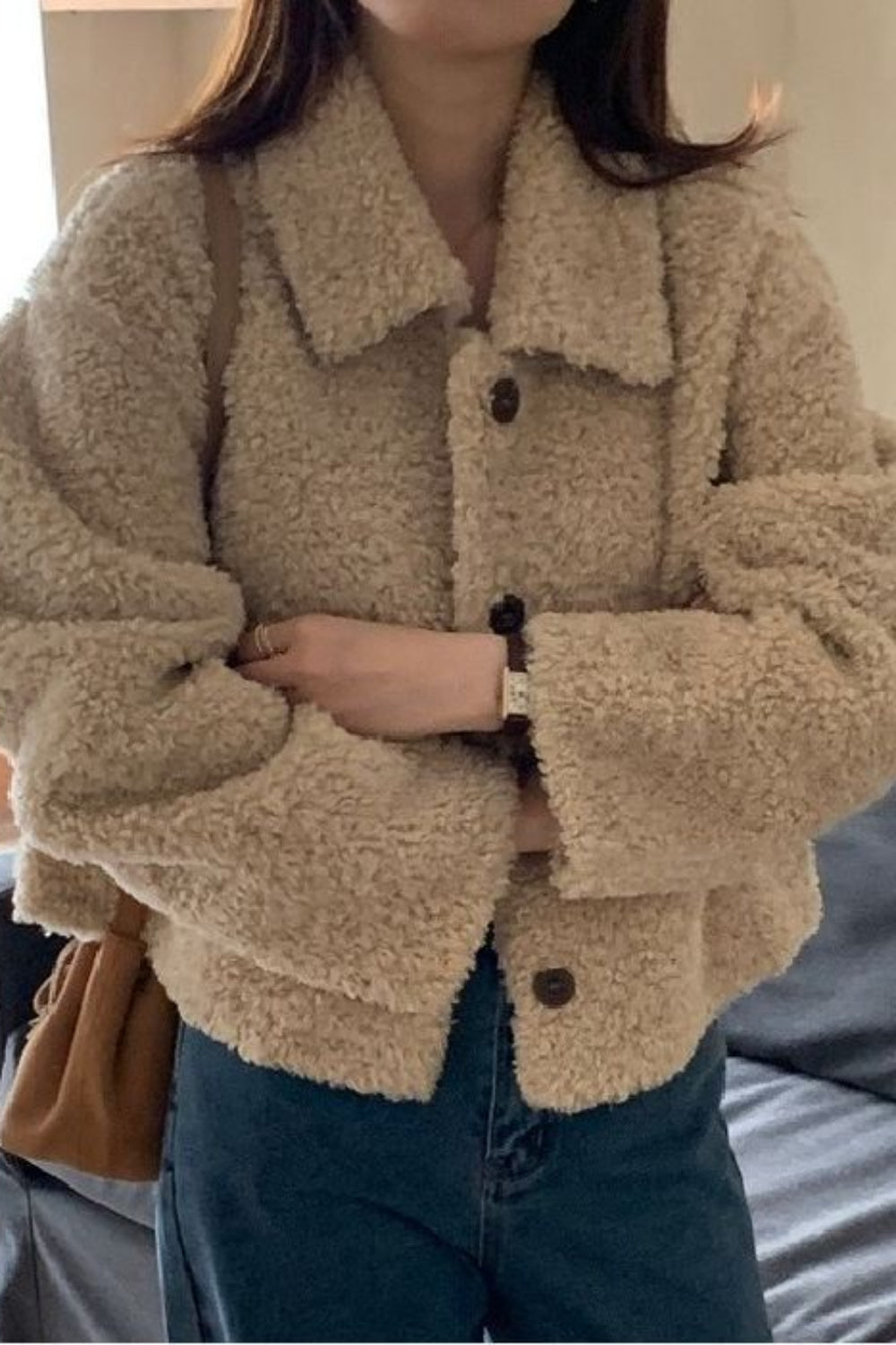 Person wearing a beige sherpa jacket indoors