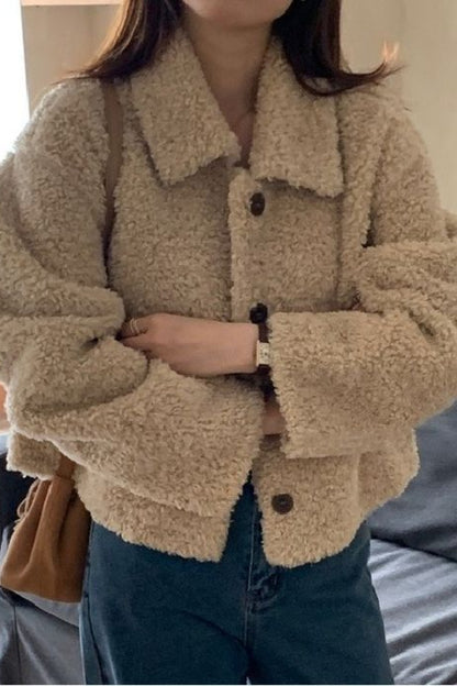Person wearing a beige sherpa jacket indoors