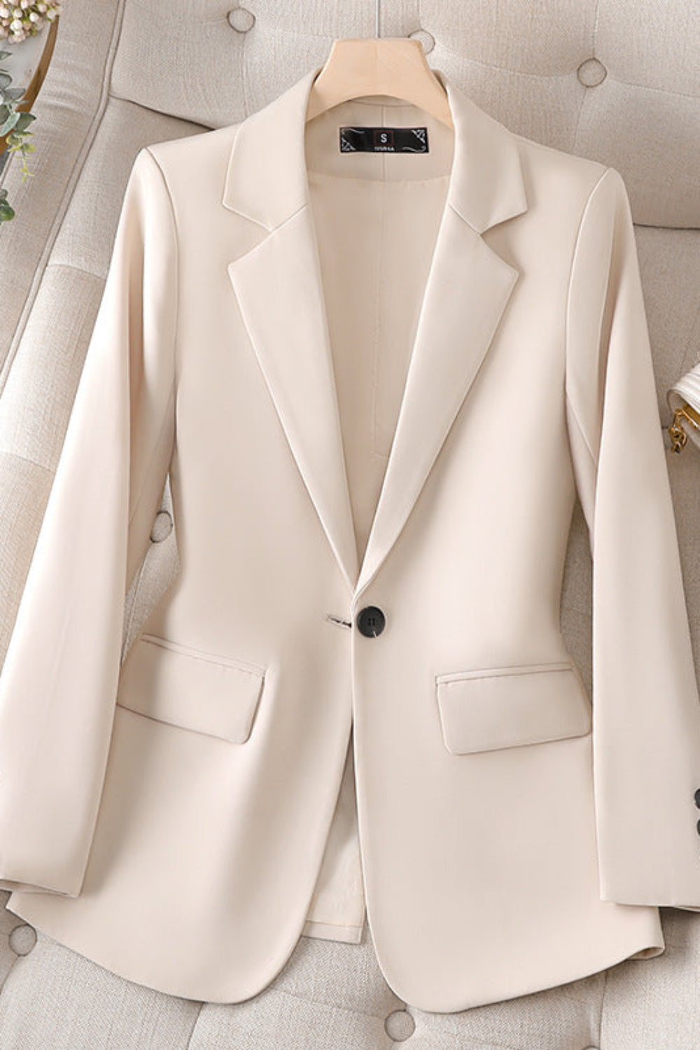 Beige blazer on a hanger with a neutral background