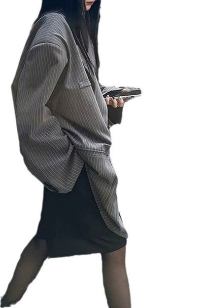 Person wearing a gray pinstripe coat over a black dress on a white background