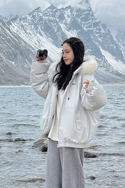 Person taking a photo of a scenic lake with mountains in the background