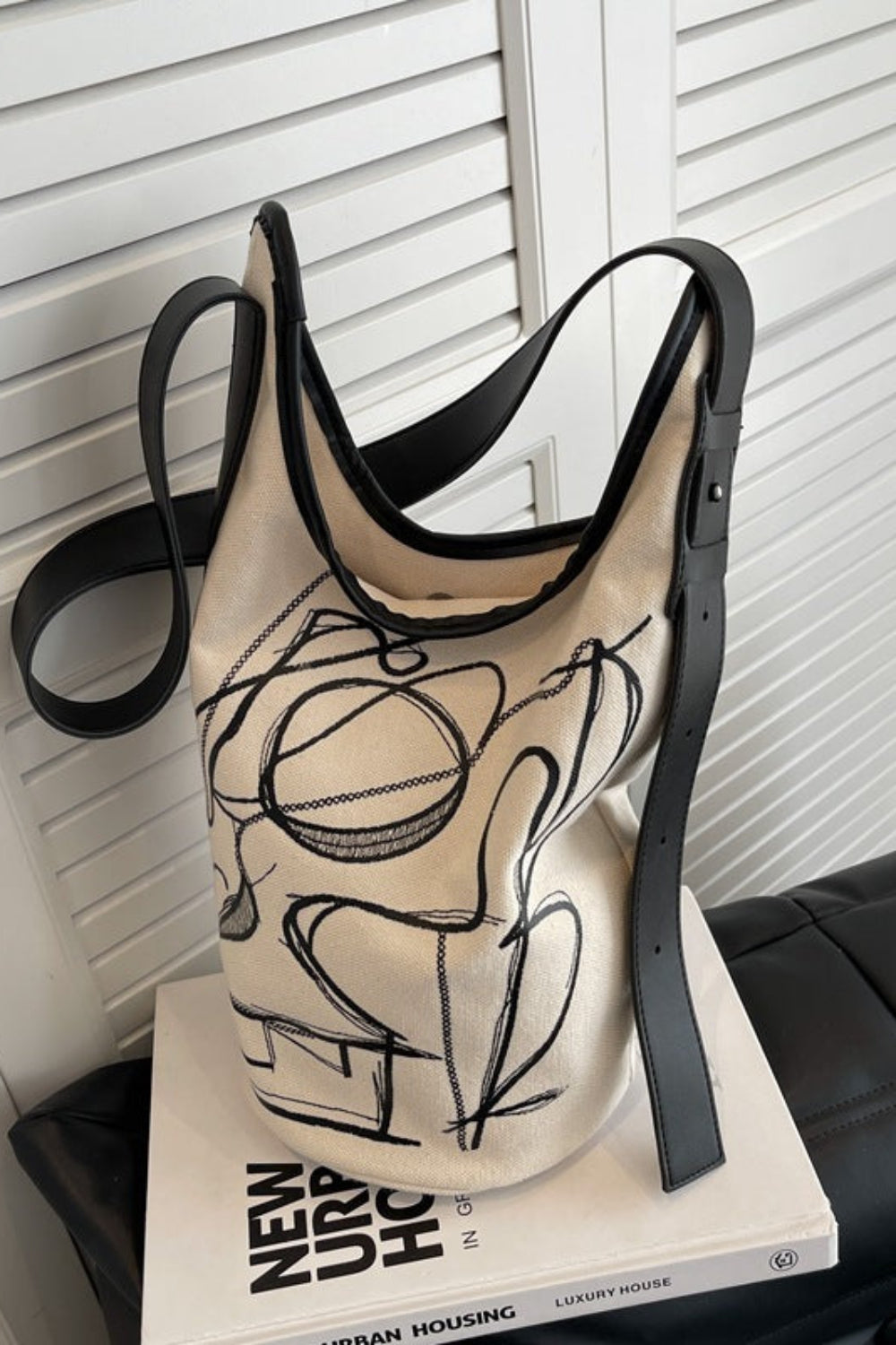 Beige tank top with black abstract design on a white surface with a book underneath.