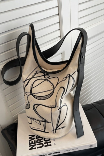 Beige tank top with black abstract design on a white surface with a book underneath.