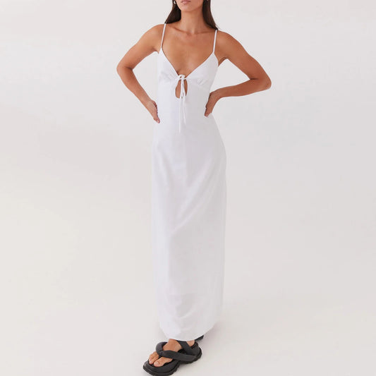 Woman wearing a white dress with thin straps on a plain background