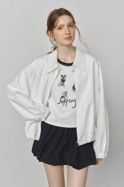 Woman wearing a white jacket over a graphic t-shirt with text and images on a plain background