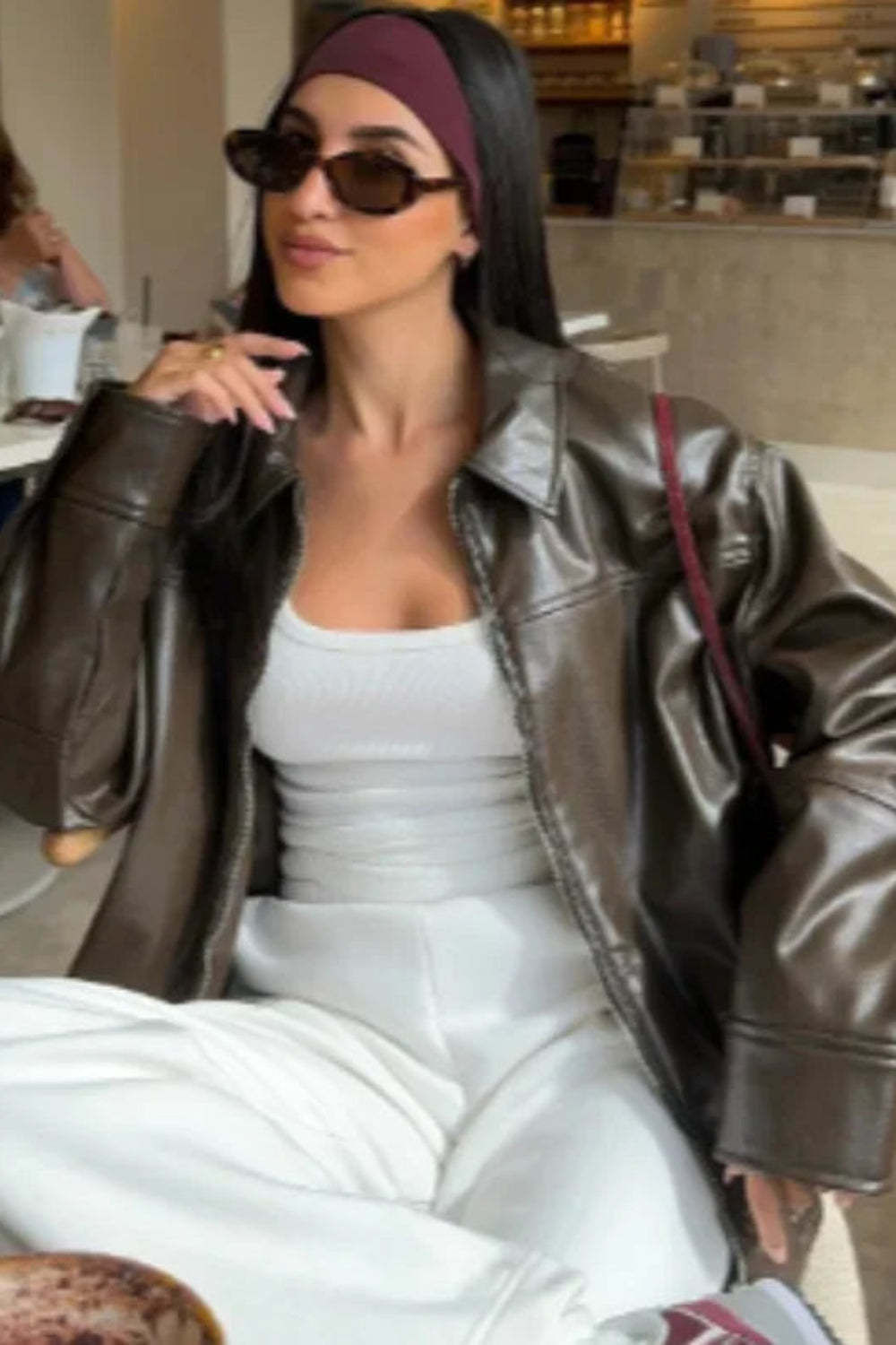 Woman in a leather jacket and sunglasses sitting in a cafe