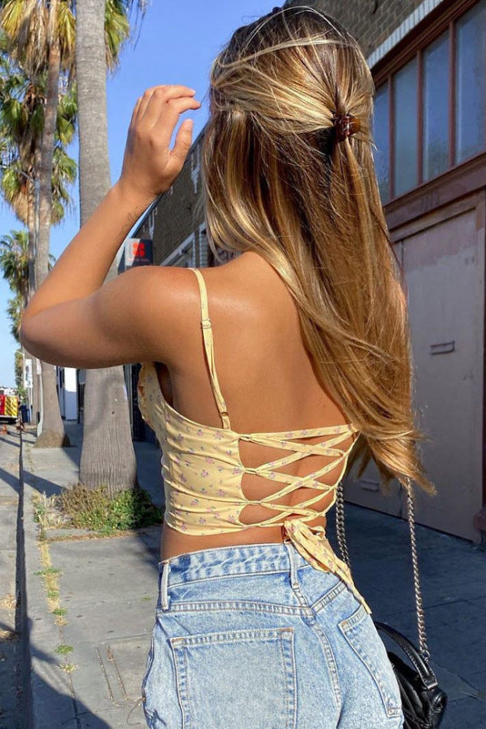 Woman walking on a sidewalk with palm trees and a building in the background