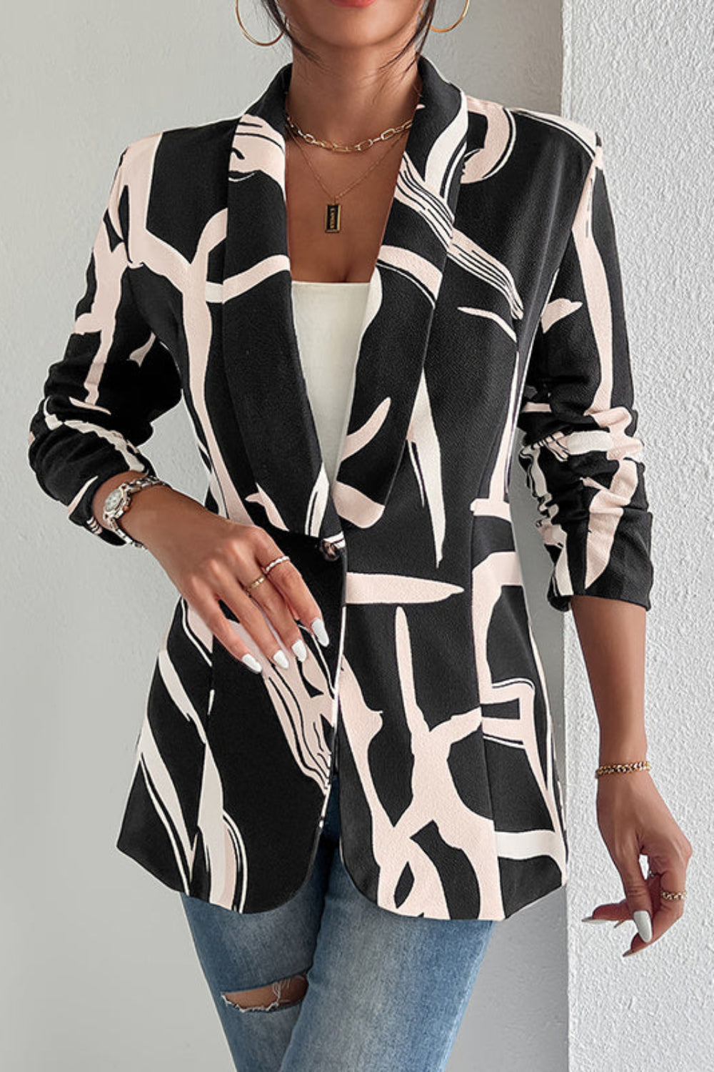 Person wearing a black and white patterned jacket against a plain background