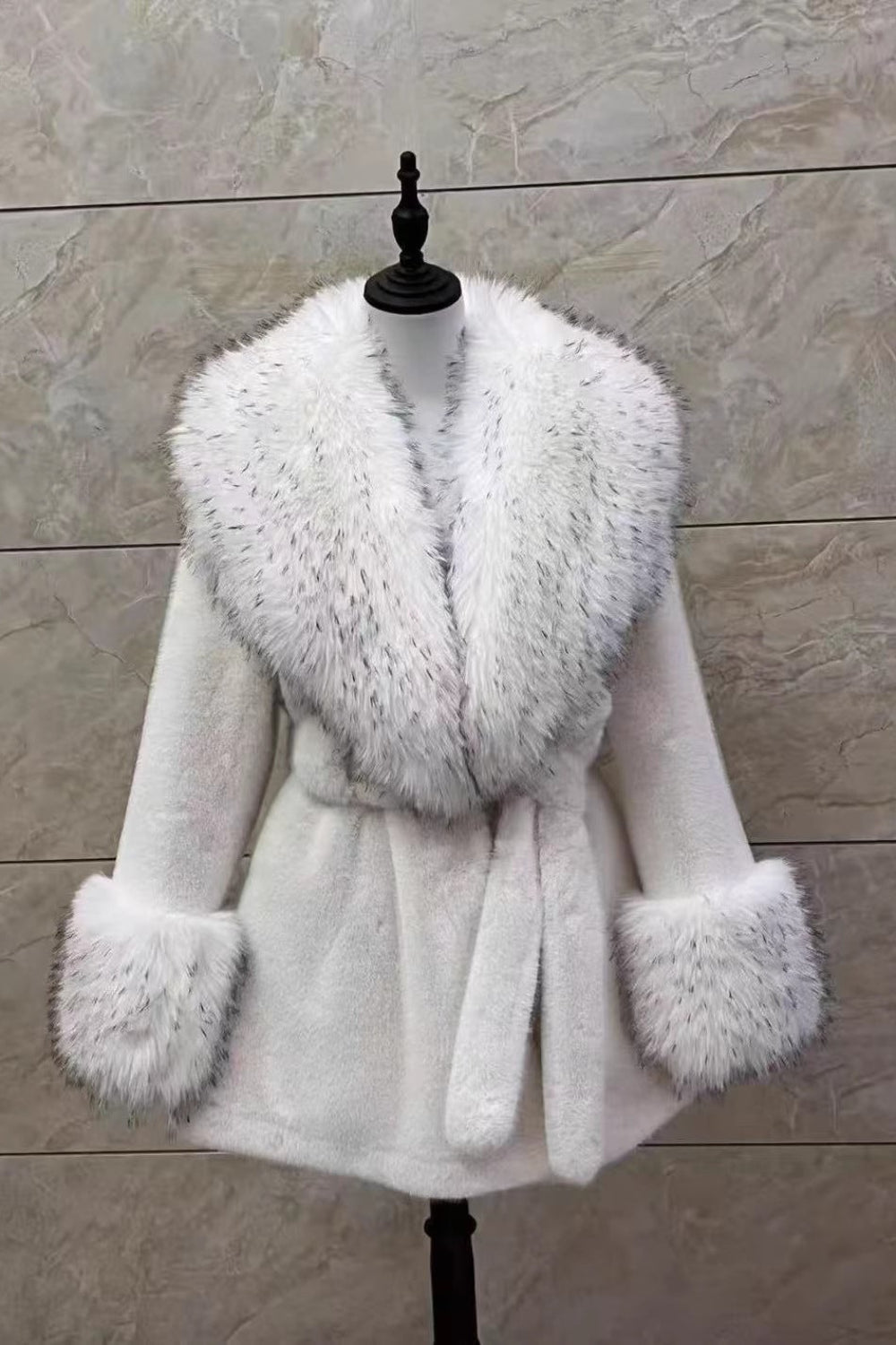 White coat with fur collar and cuffs on a mannequin against a wooden panel background