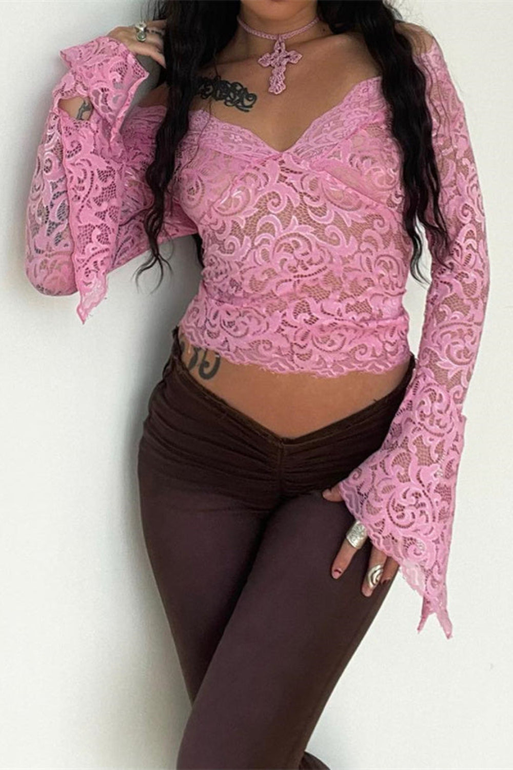 Person wearing a pink lace top with long sleeves on a white background