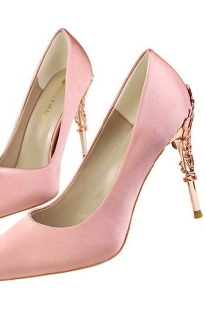 Pair of pink high-heeled shoes with decorative straps on a white background