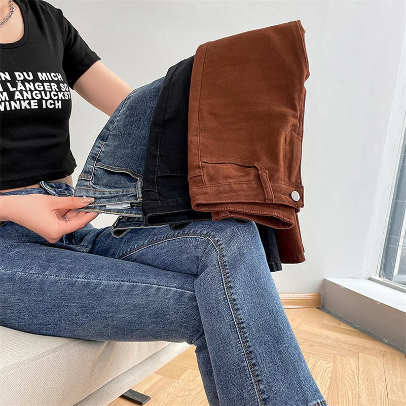 Person sitting on the floor wearing blue jeans and a black t-shirt, holding a brown jacket.
