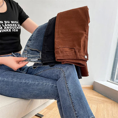 Person sitting on the floor wearing blue jeans and a black t-shirt, holding a brown jacket.