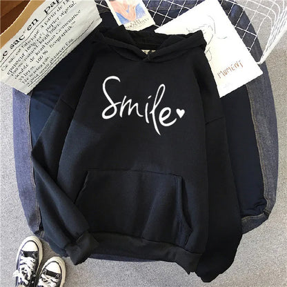 Black hoodie with 'Smile' text on a gray surface with denim and paper in the background