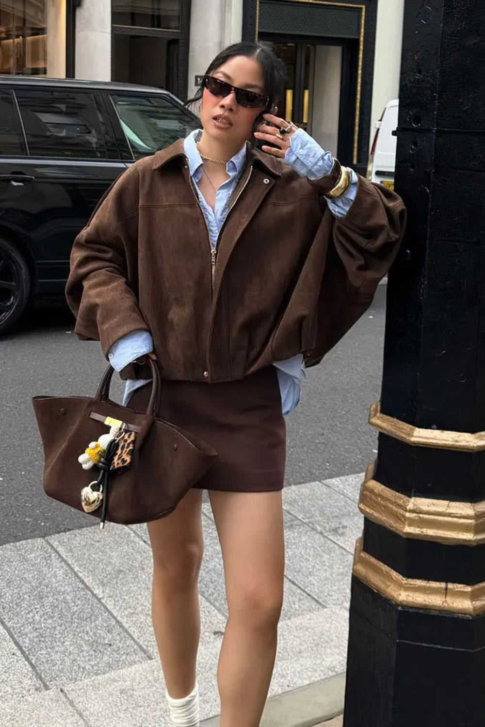 Woman in a brown outfit with a matching handbag on a city street.