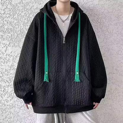 Person wearing a black textured hoodie with green drawstrings against a light gray background